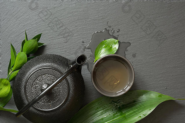 绿色日本茶黑色的板岩背景黑色的茶壶碗绿色茶前视图复制空间
