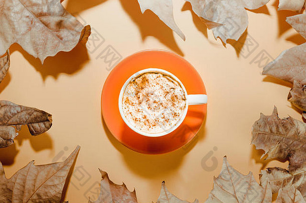 咖啡杯咖啡色背景的秋叶图案。平铺