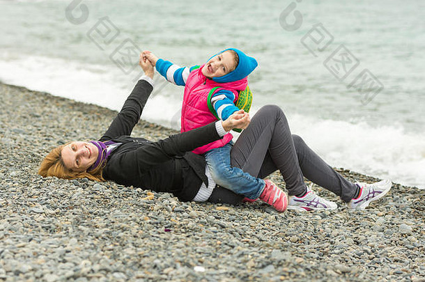 五年女孩妈妈。有趣的海滩卵石海滩冷天气