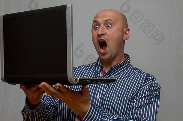 吃惊的男人看着笔记本电脑惊讶的张<strong>大嘴巴</strong>和<strong>大</strong>眼睛
