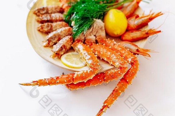 红色<strong>帝王蟹</strong>和虾放在一个盘子里，上面放着柠檬和莳萝。白色背景