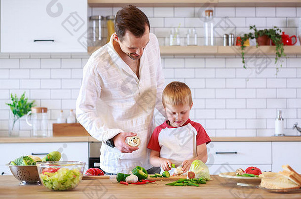 照片年轻的父亲儿子烹饪表格蔬菜