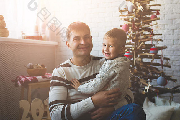 微笑的男孩和他的父亲在圣诞树旁