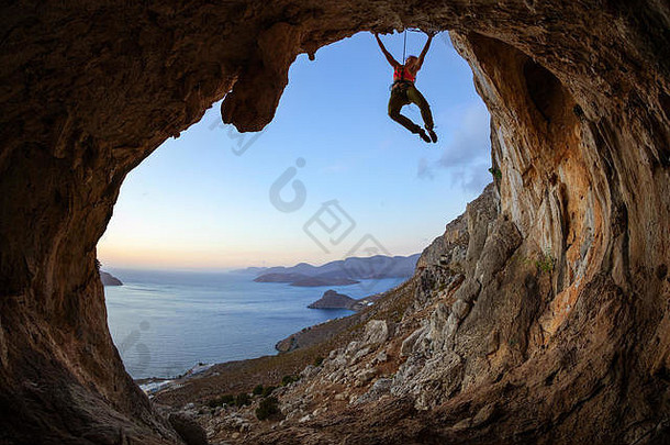 年轻的女人攀爬天花板洞穴日落卡利姆诺斯岛希腊