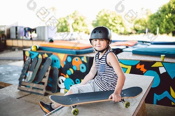 男孩坐着滑板运动场地相机孩子休息滑冰董事会滑冰公园孩子坐在斜坡休息培训滑板时尚的