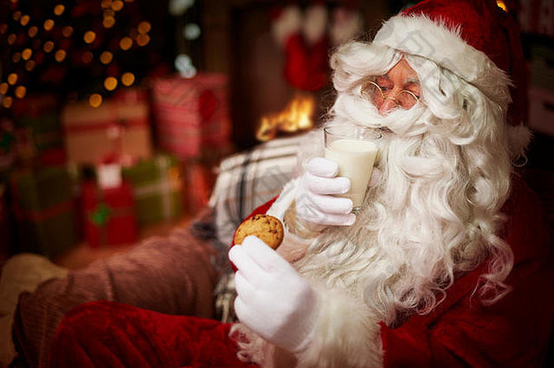 圣诞老人端着一杯牛奶和甜饼干