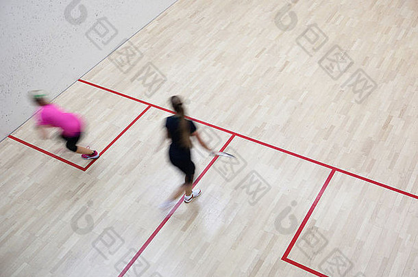 两名女子壁球运动员在壁球场上快速动作（运动模糊图像；彩调图像）