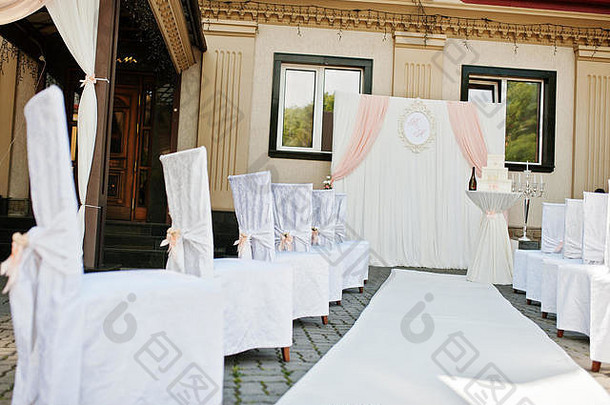 现场婚礼上带粉红结的婚礼椅。