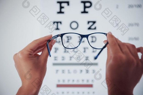 美丽的焦点眼镜女人手持有眼镜背景眼睛图表