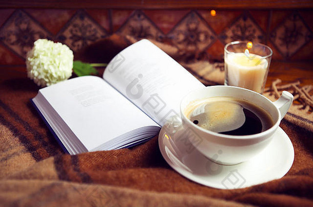 食品、卫生和舒适概念。家里有咖啡、书、格子布和蜡烛