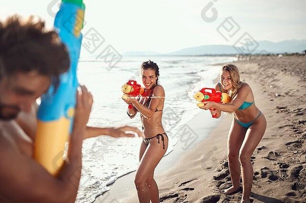两名白人妇女在沙滩上向一名男子投掷水