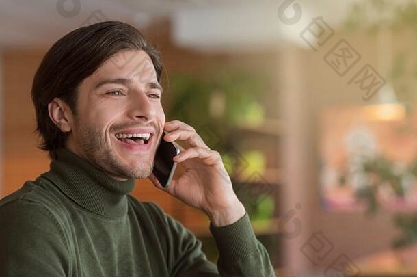 微笑的年轻人在咖啡馆打电话的照片