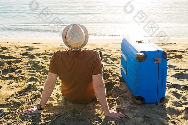 海滩上拿着手提箱的男人。<strong>暑期旅游</strong>与度假理念