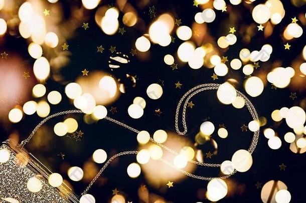 喜庆的夜晚，黑色上点缀着星星的金色离合器。节日和庆典、豪华配件和派对理念。圣诞节和新年庆祝活动。带节日灯饰的水平灯