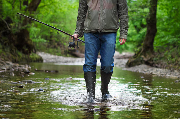 渔夫穿着雨靴在山河上用苍蝇捕鱼。春天