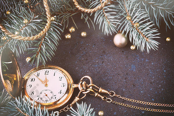复古手表，黑色节日背景上显示五到十二只，圣诞树枝和金色装饰。色调图像，文本空间