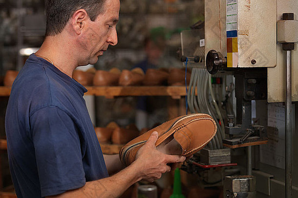 一个在鞋厂工作的成年人，检查<strong>产品质量</strong>