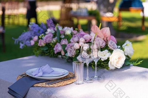 节日餐桌的装饰。玻璃花瓶和鲜花。户外节日的装饰。