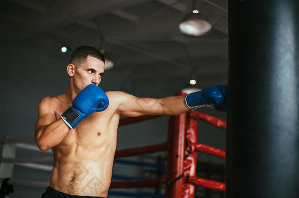 男拳击手在拳击室击打拳击袋。运动训练理念