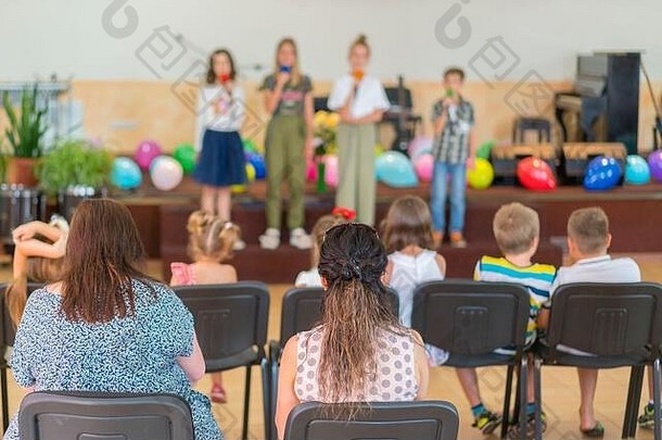 小学儿童假期。舞台上的孩子们在父母面前表演。学校舞台上的模糊儿童秀图片，作为背景