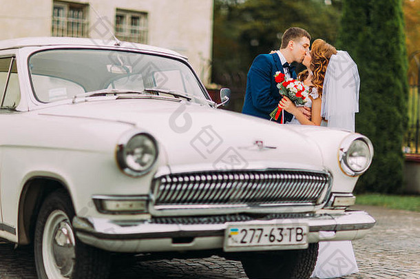 幸福的新婚夫妇在老式汽车旁接吻