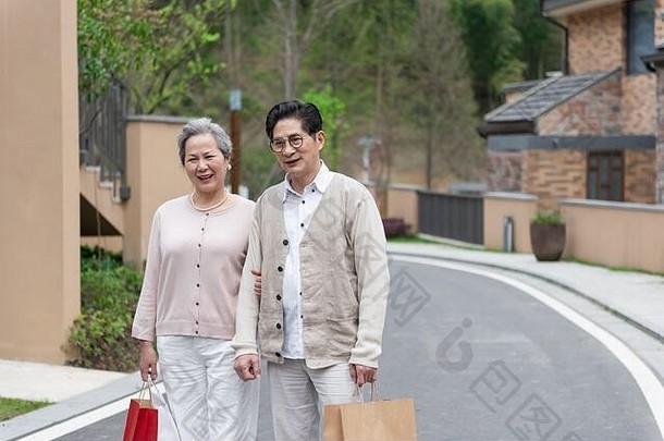 社区里一对拿着购物袋的亚洲老年夫妇