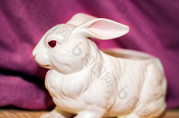 白色陶瓷兔，粉红色背景，木地板，红眼睛