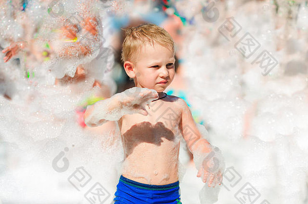 海滩上的泡沫派对。小男孩在泡沫中嬉戏跳舞。