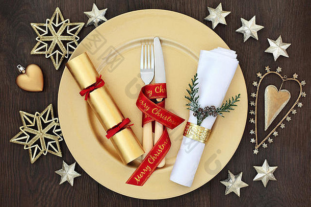 圣诞节晚餐的地方设置黄金板餐具红色的丝带餐巾环雪松用钉子钉上饼干黄金小玩意装饰橡木