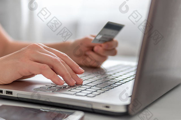 在线购物概念特写镜头女人的手持有信贷卡移动PC键盘在线购物