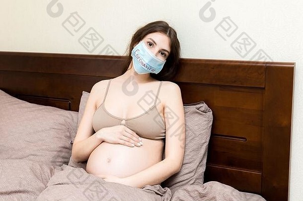 戴有冠状病毒防护口罩的孕妇因感觉不舒服而卧床休息。全球流行病概念。检疫概念