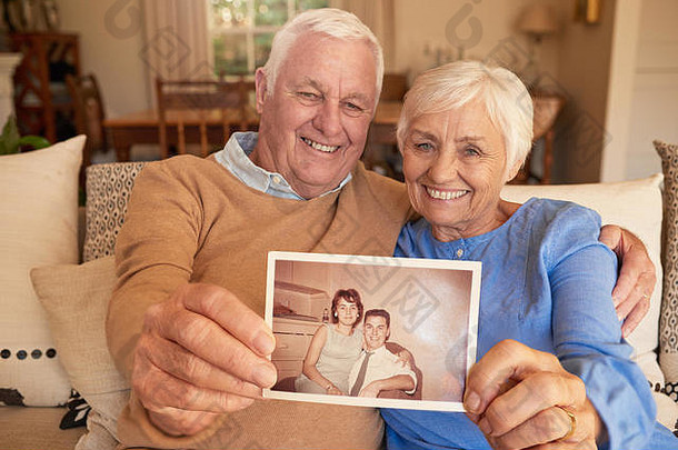 面带微笑的老年夫妇拿着他们年轻时的照片