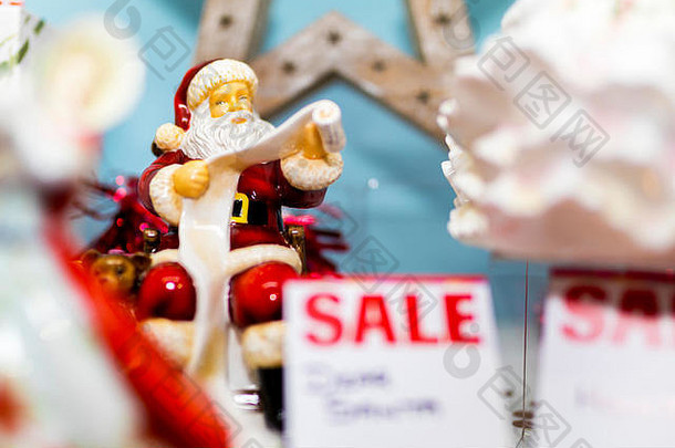 在英国一家购物中心的橱窗里，一个陶制或骨瓷的圣诞老人正在阅读正在出售的淘气或可爱的清单