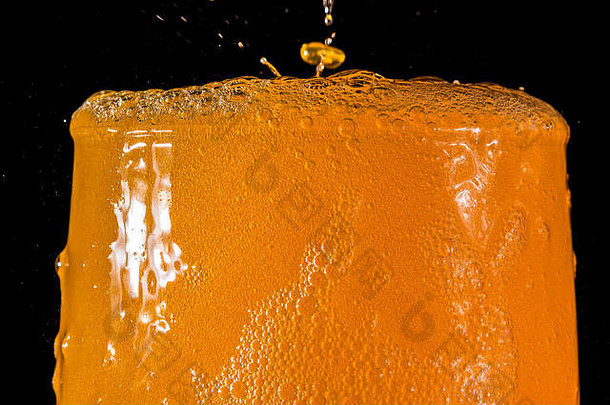 橙色苏打水大玻璃满溢的玻璃橙色苏打水特写镜头泡沫孤立的黑色的背景