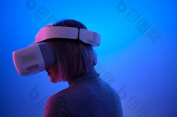 在虚拟现实中，一名年轻女子戴着虚拟现实<strong>眼镜</strong>触摸空气，在蓝色背景空间特写工作室照片上体验隔离。女孩哈夫