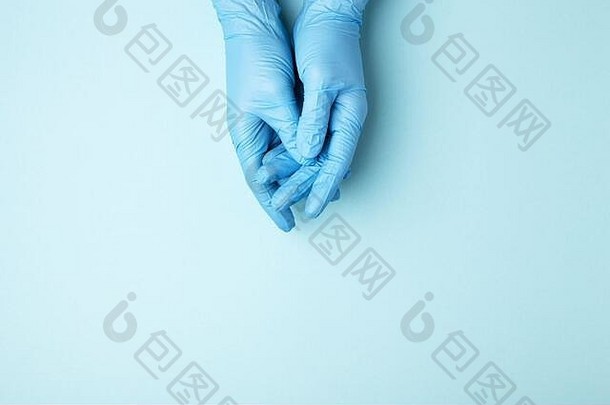 医生的手戴着医用手套，蓝色背景，有复印空间。
