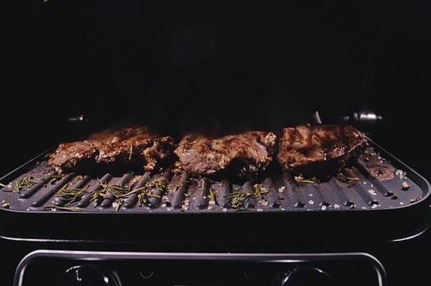 美味的多汁的肉牛排烹饪烧烤主要的牛肉弗莱电烘烤器迷迭香黑色的胡椒盐慢运动