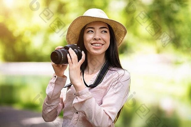 户外爱好。快乐亚洲女旅行者用现代相机拍照
