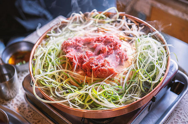 首尔韩国餐厅的牛肉烤肉bulgogi，铜锅上的生活方式新鲜韩国美食，带切片烤架，特写，空间