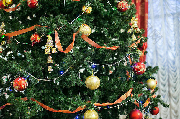 新年，礼物，庆祝概念。用红色和金色的球、小铃铛、卷曲的丝带和五颜六色的闪烁灯装饰的圣诞树令人惊讶