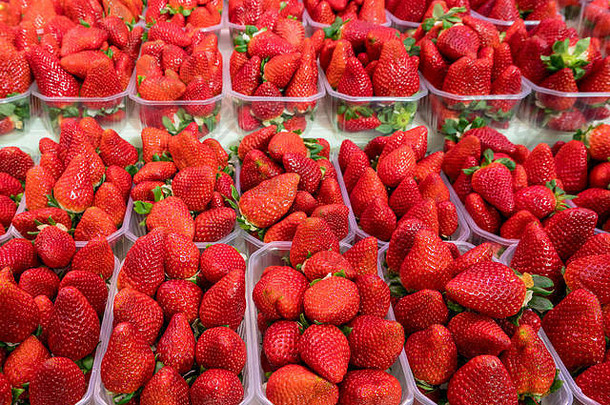 市场摊位上塑料盒中的草莓