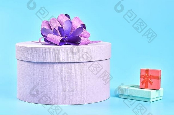 圆形礼品盒，带蝴蝶结和两个小礼品盒。蓝色背景上的紫色礼品盒。任何节日的惊喜套餐：生日，淡水河谷