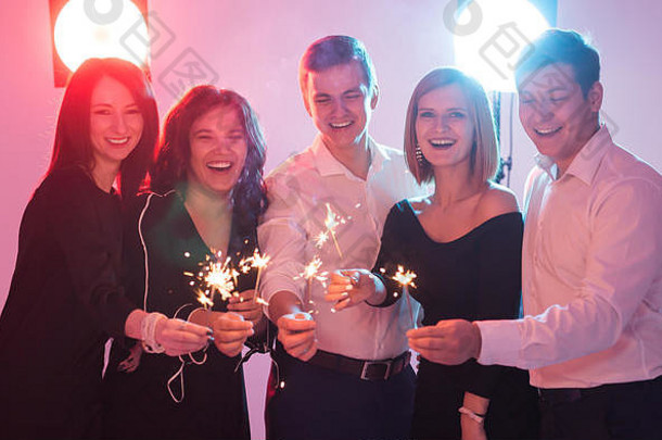 开心地庆祝。一群兴高采烈的年轻男女拿着火花。新年、假期和派对概念。