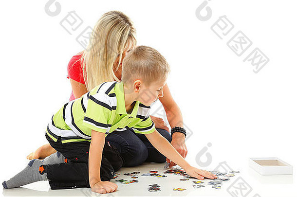<strong>妈妈</strong>。玩谜题玩具儿子地板上孤立的白色背景