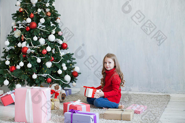 小女孩在圣诞树新年度假屋打开圣诞礼物
