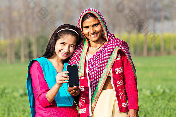 微笑农村妈妈。十几岁的女儿显示智能手机农场村
