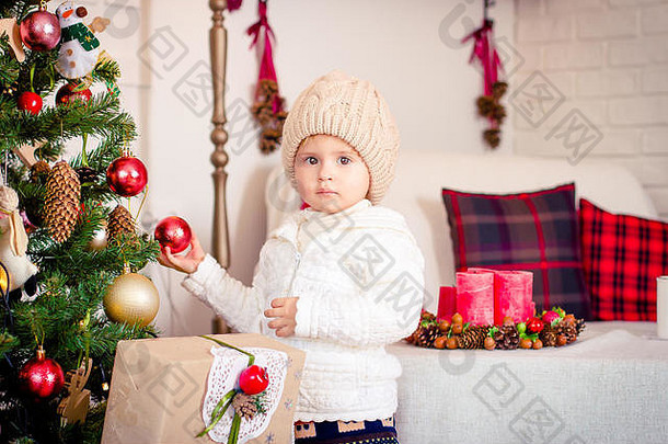 小女孩在装饰圣诞树，背景是枕头的沙发。