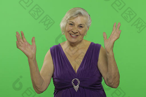 上了年纪的女人显示惊讶的是快乐微笑漂亮的快乐祖母紫色的衣服的地方标志文本浓度关键绿色屏幕背景