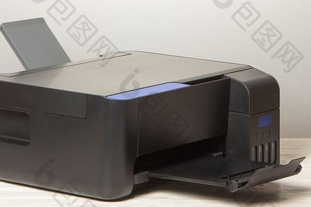 白色木桌上的黑色复印机，特写。