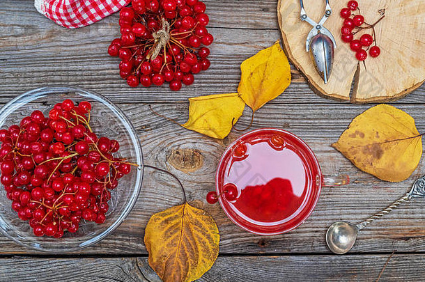 透明玻璃杯中的维本鲜浆果茶，灰色木桌上的鲜红色浆果，俯视图，预防和治疗感冒